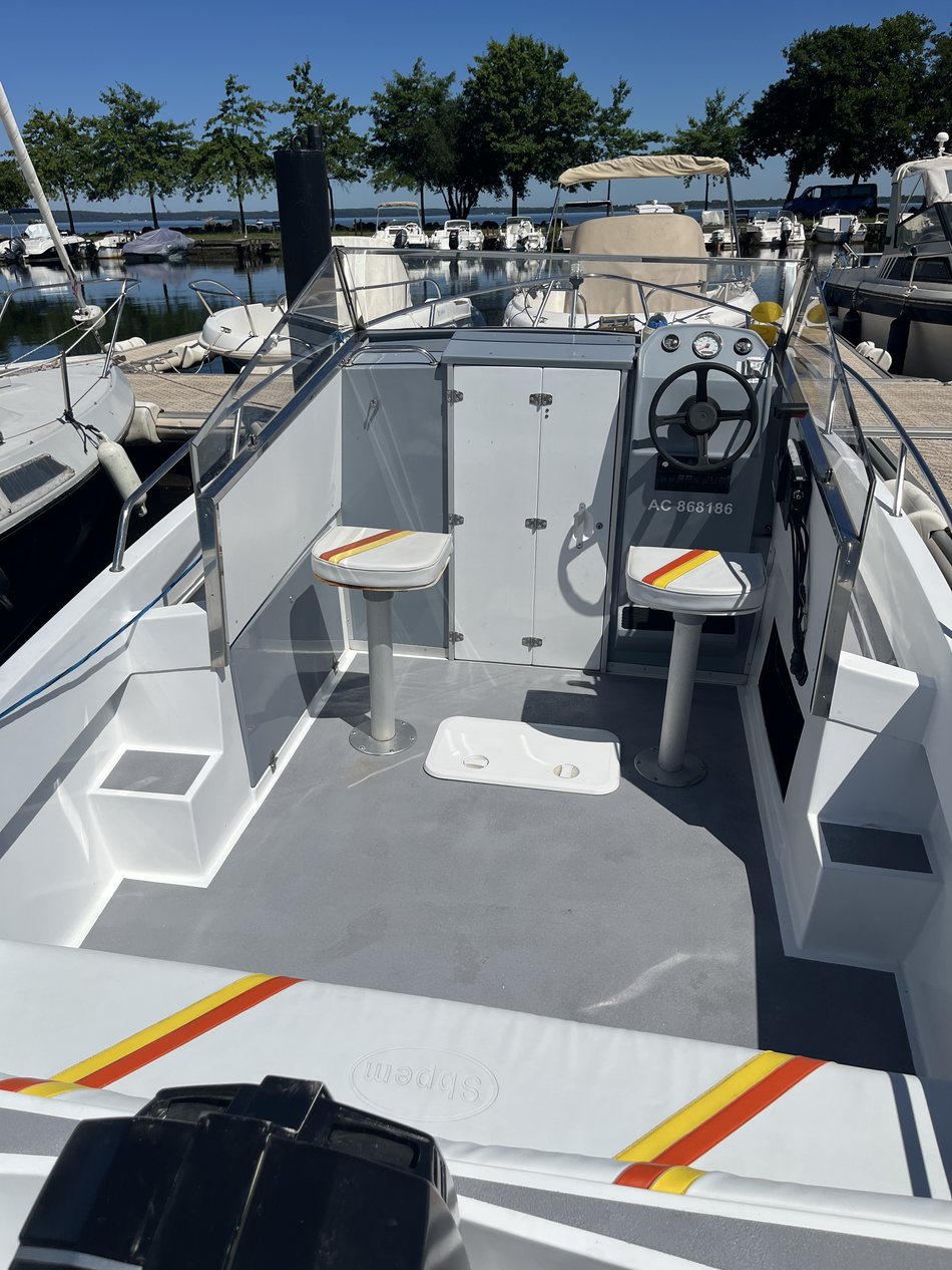 Poste de pilotage du bateau : volant, siège de barre et cockpit vus depuis l'avant